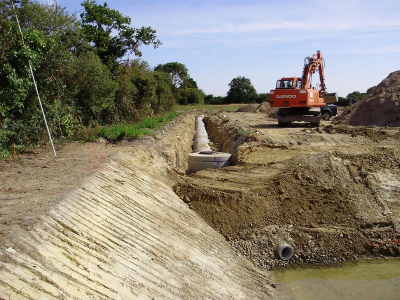 Tranchée de terrassement avec canalisation et pelle orange