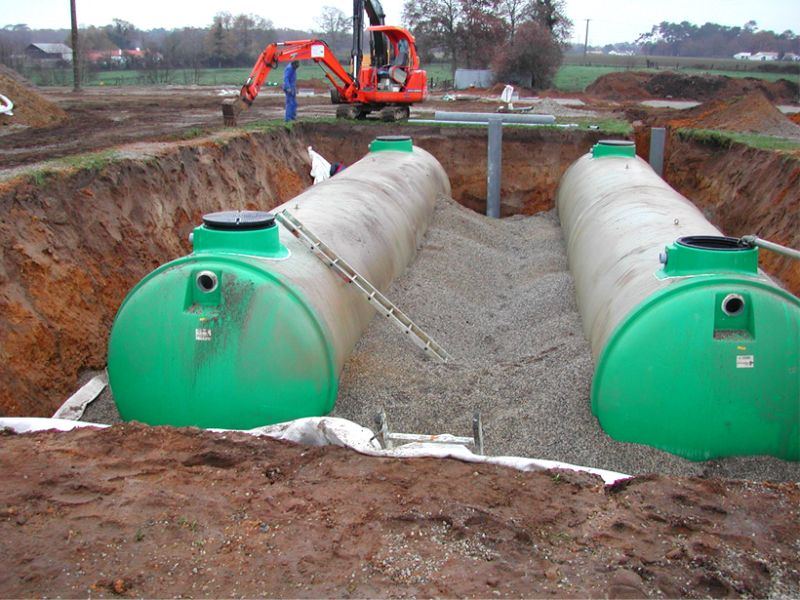 Deux cuves vertes d'une installation d'assainissement individuel posées en fouille