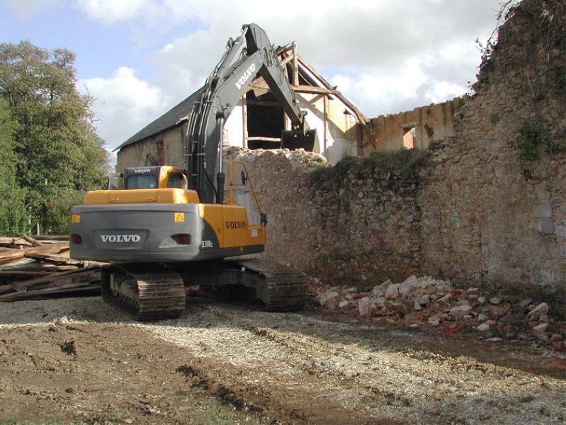 Pelle Volvo abattant un mur de pierre d'un ancien bâtiment
