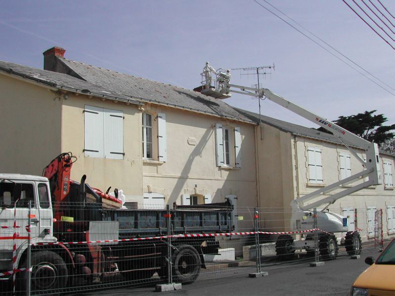 Retrait de la toiture d'une maison : nacelle et camion-grue en façade