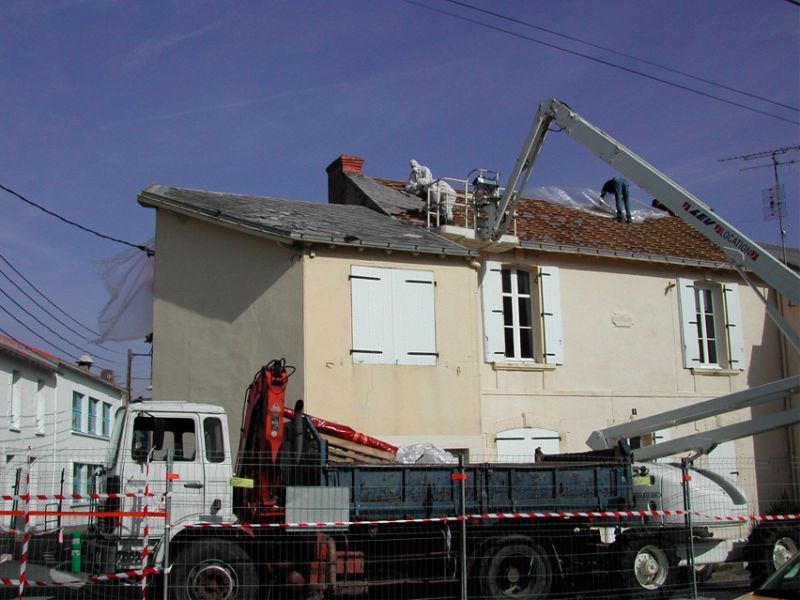 Camion-grue et nacelle pendant le retrait d'une toiture de maison