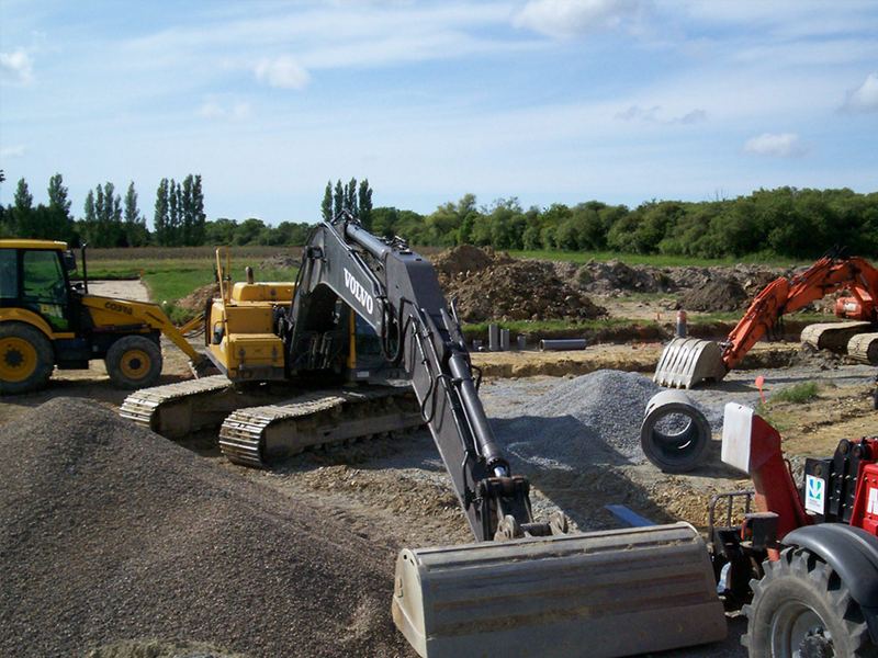 Pose d'une canalisation en béton, pelle et camion sur la tranchée